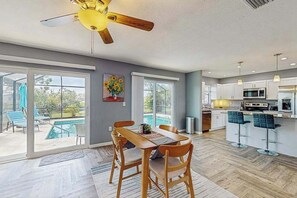 A modern kitchen with a dining area, large windows, and a ceiling fan. - Dog friendly house with private pool, lanai, and washer & dryer (Rotonda West)