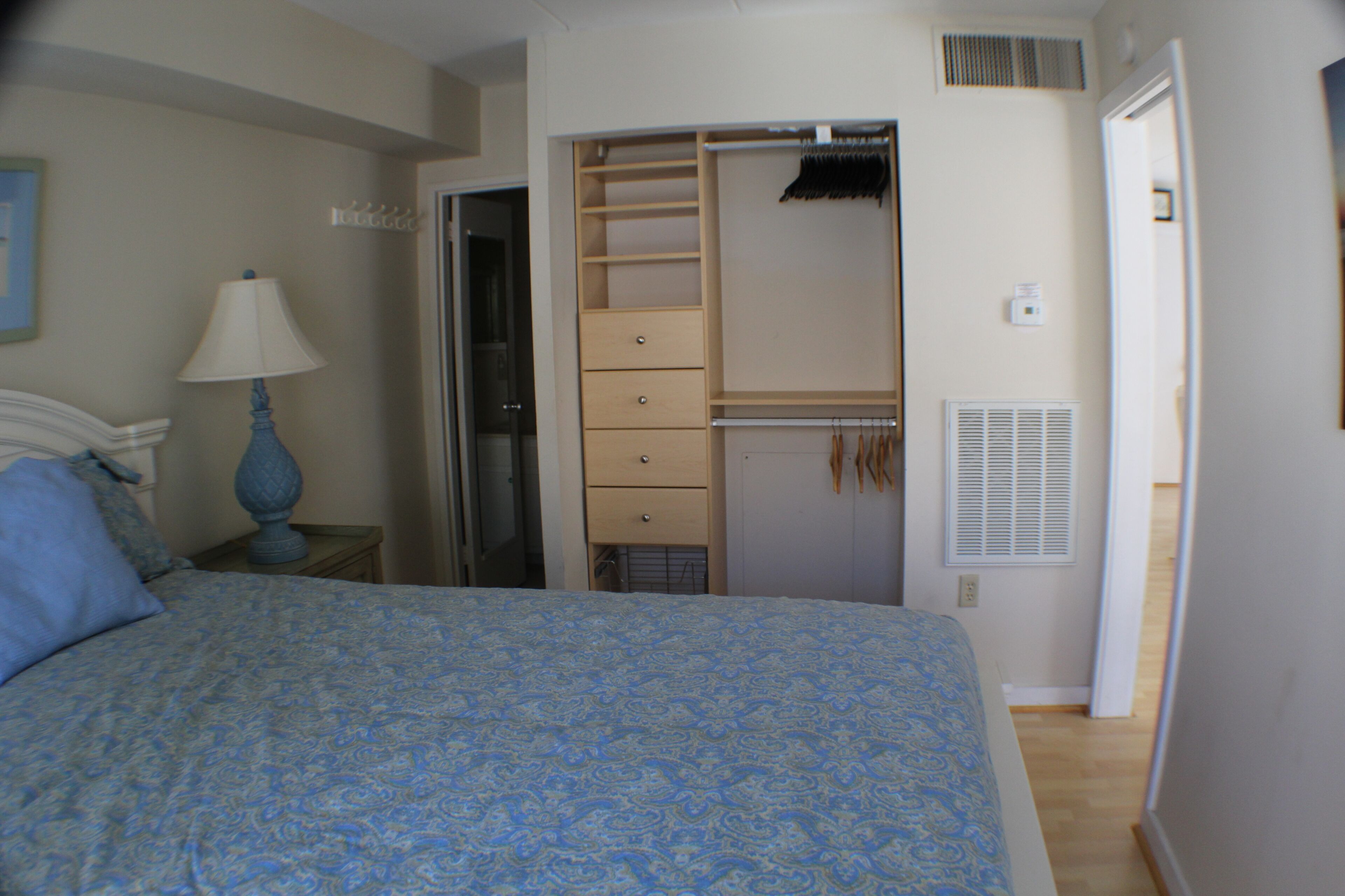 Une chambre à coucher comprenant un lit, une table de chevet, une lampe, une armoire et un placard.