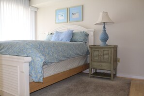 Ein Schlafzimmer mit einem Bett, einem Nachttisch und zwei gerahmten Bildern an der Wand.