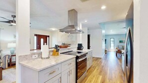 Una cucina moderna con una grande isola, elettrodomestici in acciaio inossidabile e pavimento in legno.