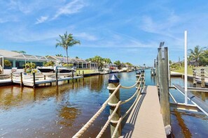 A marina with docked boats, a wooden walkway, and a glass-roofed building. - Coastal Cabana - canal-front home with private heated pool, dock, inviting patio (Cape Coral)