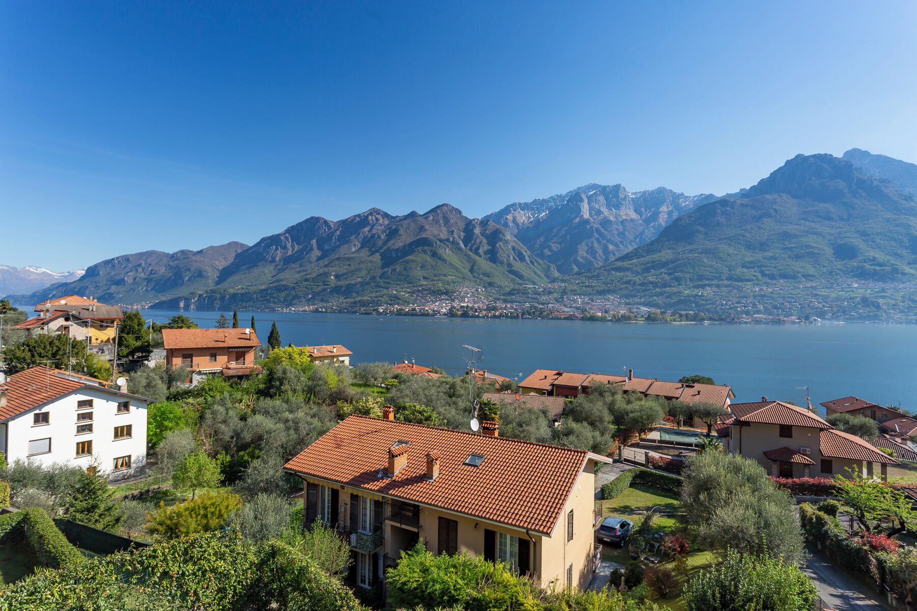 A coastal town with terraced houses, a lake, and mountains in the background.
