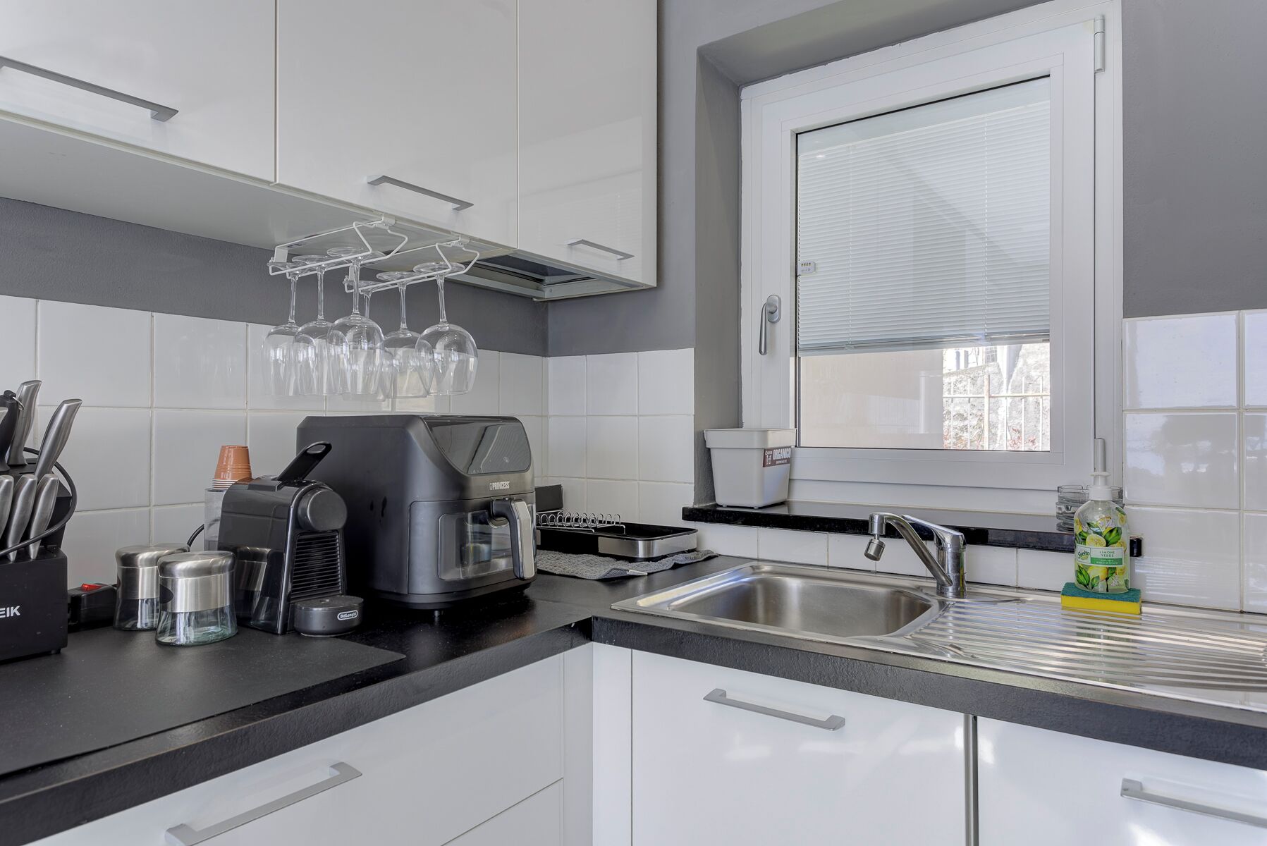 Een moderne keuken met een koffiezetapparaat, wijnglazen en een raam.