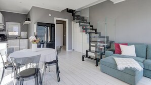 Een moderne woonruimte met een eethoek, een bank, een trap en een keuken.