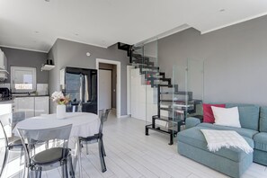 A modern living space with a dining area, a sofa, a staircase, and a kitchen. - Open View Apartment by Wonderful Italy (Onno)