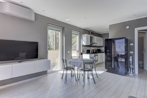 A modern kitchen with a large refrigerator, a dining area with a table and chairs, and a flat-screen TV mounted on the wall. - Open View Apartment by Wonderful Italy (Onno)