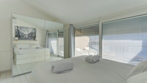 Een moderne hotelkamer met een groot bed, een glazen scheiding en uitzicht op de stad.