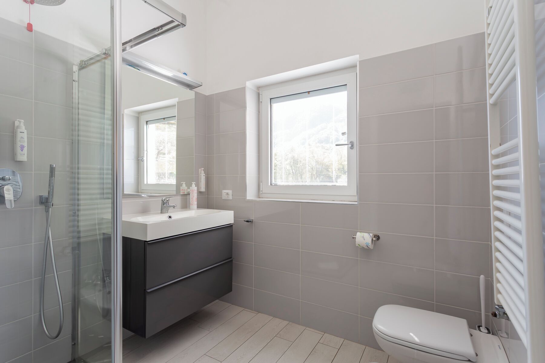 Une salle de bain moderne avec une douche à parois de verre, un lavabo blanc et des toilettes.