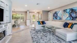 A modern living room with a white sectional sofa, a glass coffee table, and abstract art on the wall.