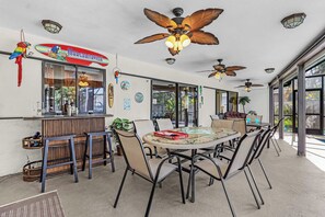 A restaurant with a bar area, multiple ceiling fans, and a dining table with chairs. - Cape Escape - Dog-Friendly | Pool, Bar & Fenced Yard (Cape Coral)