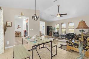 A spacious living area with a dining table, seating, and a ceiling fan. - Cape Escape - Dog-Friendly | Pool, Bar & Fenced Yard (Cape Coral)