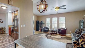 A spacious living area with a dining table, sofas, a ceiling fan, and a kitchen in the background. - Dog-friendly home with a private heated pool, screened lanai, W/D, & AC (Cape Coral)