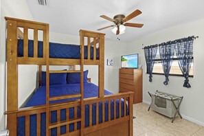 A bunk bed with a ceiling fan, a television, and a window with curtains. - Cape Escape - Dog-Friendly | Pool, Bar & Fenced Yard (Cape Coral)