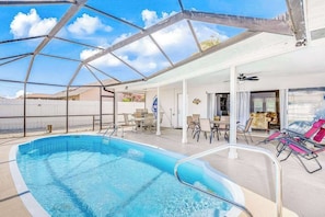 An indoor swimming pool with a glass ceiling, lounge chairs, and a patio area. - Snowbird-friendly home with enclosed yard, pool, patio, AC, & WiFi - 2 dogs OK (Cape Coral)