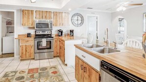 Uma cozinha moderna com armários de madeira, eletrodomésticos de aço inoxidável, uma ilha central com pia e um ventilador de teto.