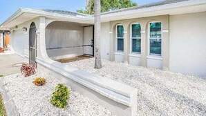 Uma casa térrea com garagem, varanda coberta e entrada por um caminho de cascalho.