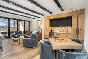 Un salon moderne avec une table basse en bois, des canapés gris et un jeu d’échecs.