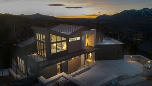 Ein modernes Mehrfamilienhaus mit großen Fenstern, einem Balkon und Blick auf Berge.
