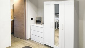 A hallway with a white wardrobe, a mirror, and a wooden door.