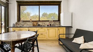 A kitchen with a dining table, chairs, a sofa, and a window with a view.