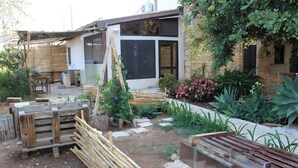 A garden with wooden furniture, a pergola, and a modern house with large windows.