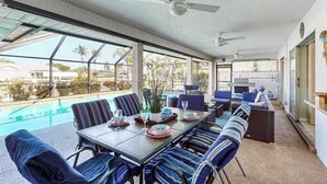 A spacious outdoor dining area with a pool view, ceiling fans, and a mix of seating options. - Two Family Rooms ! Saltwater Pool ! (Cape Coral)