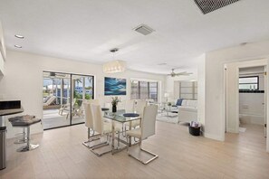 A modern interior with a dining area, a kitchen, and a living space with a view. - Dog friendly house with private pool, large dock, and Gulf access (Cape Coral)