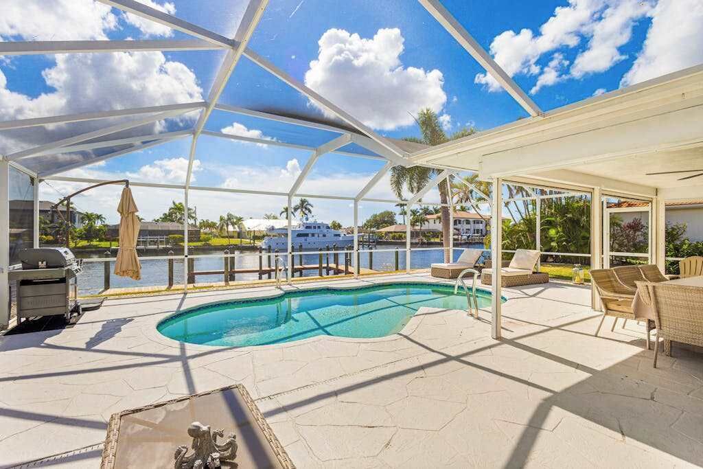 Una piscina scoperta coperta, con poltrone da relax e un'area barbecue.