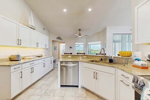 A modern kitchen with white cabinets, a dishwasher, a built-in oven, and a ceiling fan. - Waterfront pool home, family friendly, close to beaches with AC, WD and WIFI (Englewood)