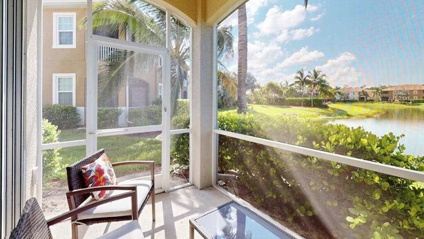 A room with a view of a lake, a chair, and a glass table. - Water-view condo with screened patio, pool, central AC, & private washer/dryer (Fort Myers)
