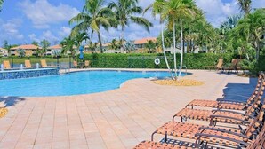 A swimming pool with lounge chairs, palm trees, and a fenced area. - Water-view condo with screened patio, pool, central AC, & private washer/dryer (Fort Myers)
