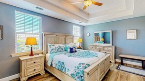 A bedroom with a bed, nightstands, a bench, a ceiling fan, and a window with blinds. - Water-view condo with screened patio, pool, central AC, & private washer/dryer (Fort Myers)
