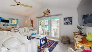 A modern living room with a sofa set, a coffee table, a ceiling fan, and a view through a glass door. - Single-story home with private yard, AC, & W/D - walk to beach, & dog-friendly (Englewood)