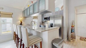 A modern kitchen with a central island, bar stools, a trash bin, and a microwave. - Single-story home with private yard, AC, & W/D - walk to beach, & dog-friendly (Englewood)