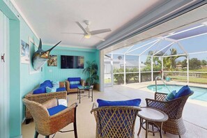 A sunlit room with wicker furniture, a ceiling fan, and a view of a swimming pool. - Snowbird-friendly home with private pool, water views, patio & sunroom (Englewood)