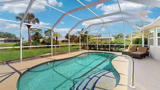Una piscina cubierta con un atractivo elemento acuático de color azul cristalino, rodeada por una estructura de metal blanco y un área de descanso con vistas al paisaje circundante.