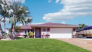 Una casa residencial con techo rojo, un garaje y un césped bien cuidado.