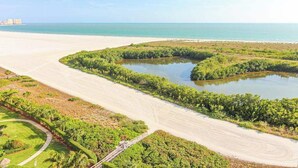 Kustlandschap met een strand, een waterpartij en een groen gebied met een pad.