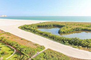 Eine Küstenlandschaft mit Strand, einem Gewässer und einer Grünfläche mit einem Weg.