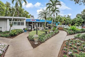 A restaurant with outdoor seating, surrounded by tropical plants and a palm tree. - Your Perfect Naples Retreat Relax at Park Shore Resort Snowbird Friendly (Naples)