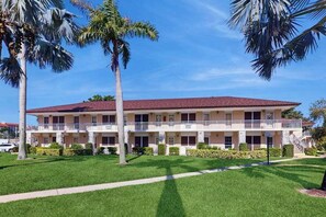 A multi-story hotel with a red roof, balconies, and a well-maintained lawn. - Charming Island Getaway | Beach, Pool & Prime Location (Marco Island)