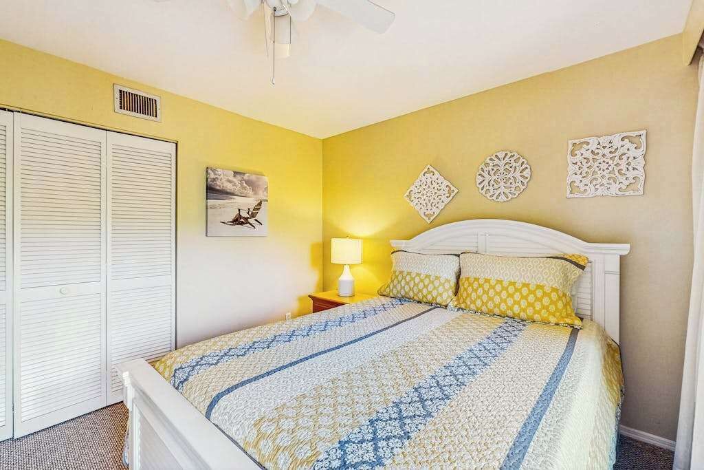 Une chambre à coucher comprenant un lit, une table de chevet, une lampe et des œuvres d’art décoratives accrochées au mur.
