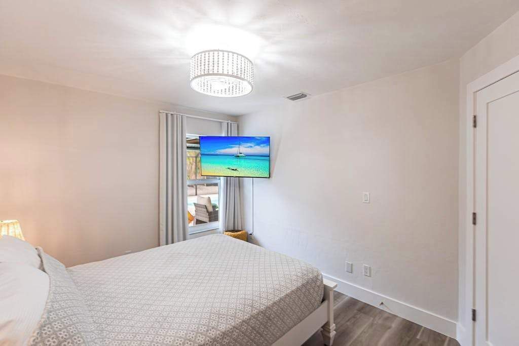 A bedroom with a bed, a television mounted on the wall, and a ceiling light fixture.