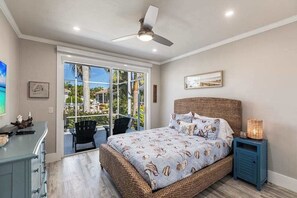 A bedroom with a large bed, a ceiling fan, a nightstand, and a view through a glass door to an outdoor area. - Elegant and luxurious waterfront home with heated pool, dog friendly, WIFI (Marco Island)
