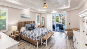 Un dormitorio con cama, mesita de noche, lámpara y vistas al exterior.