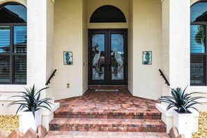 A building entrance with a double door, steps, and two potted plants. - Modern waterfront retreat has pool with spa waterfall, close to Gulf beaches (Marco Island)