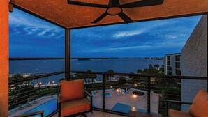Een balkon met uitzicht op zee, een plafondventilator en zitplaatsen buiten.
