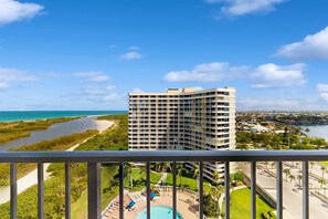 A high-rise hotel with a pool, surrounded by greenery and a view of the coastline. - Waterview condo with shared pool, pickleball, and WIFI (Marco Island)