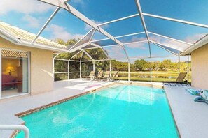 Ein Schwimmbad mit Glasveranda, Liegestühlen und Blick auf einen Golfplatz.