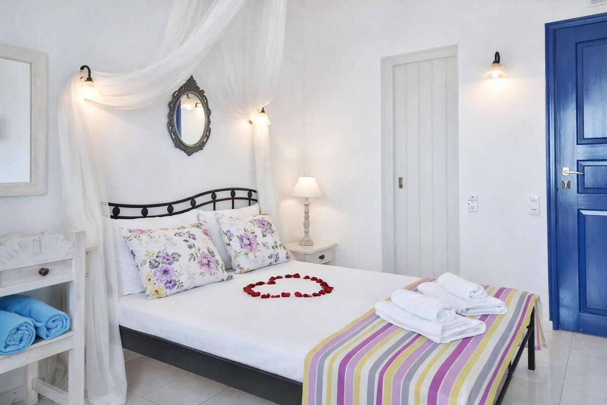 A neatly made bed with floral pillows, a bedside lamp, and a striped blanket.
